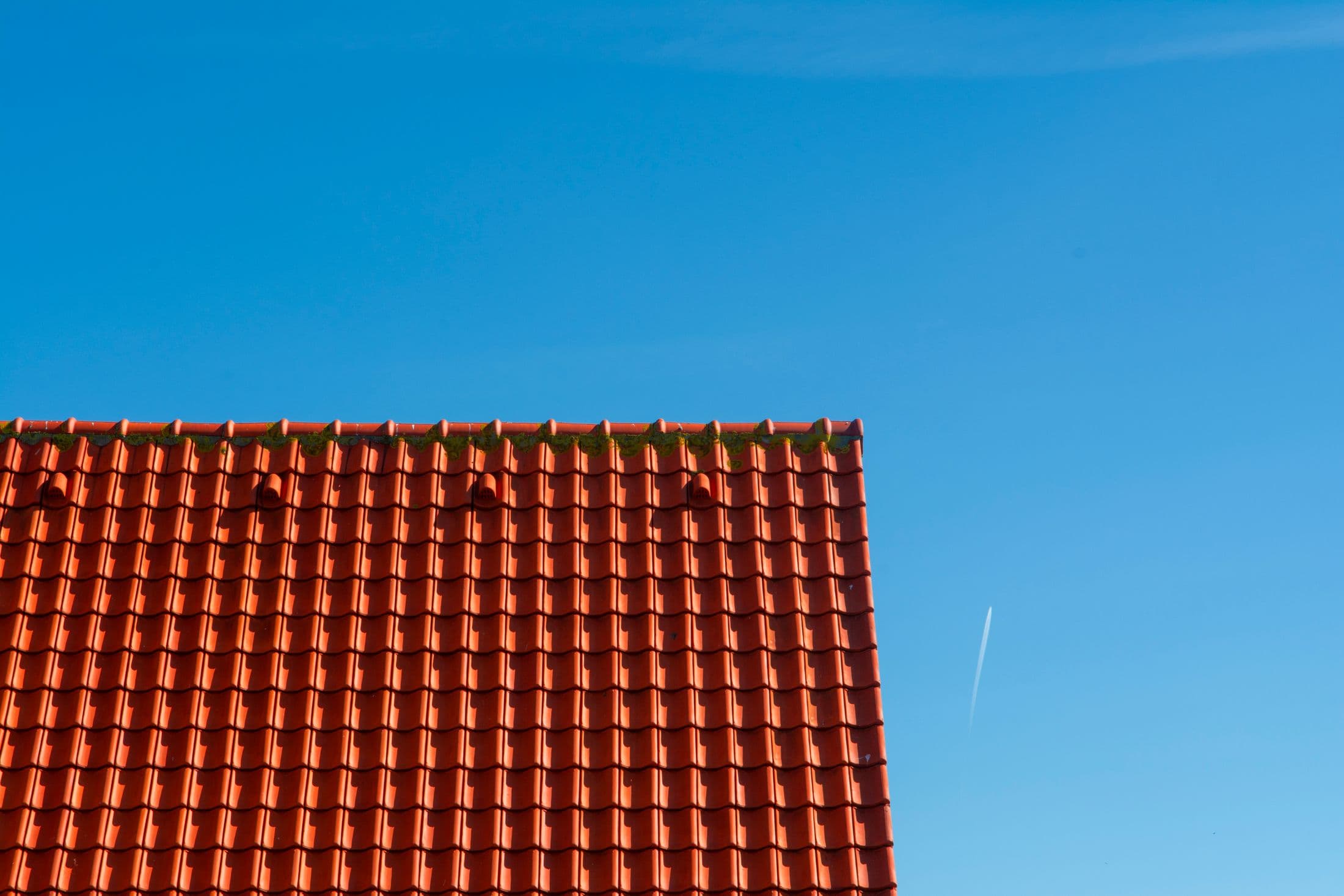 Stock photo showing red roof tiles against a clear blue sky