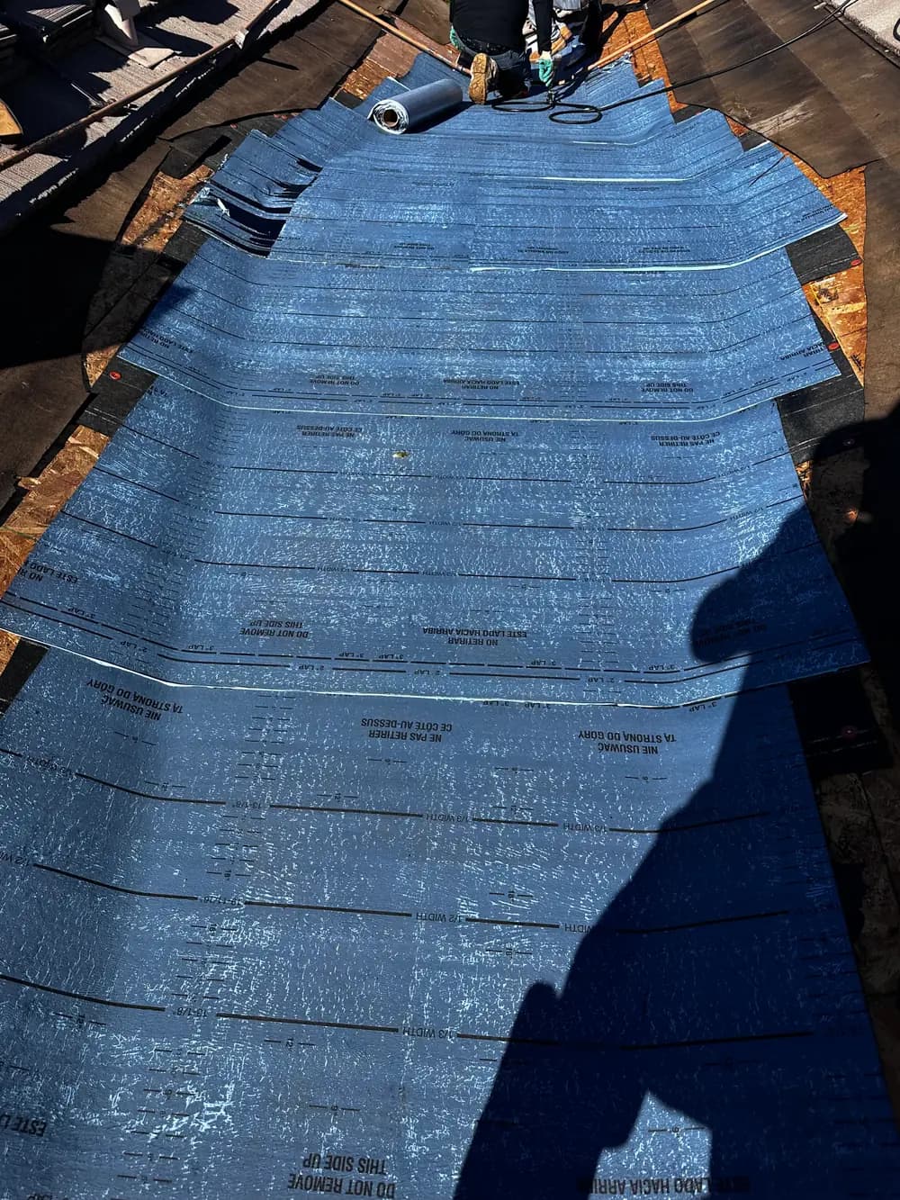 Blue roof underlayment being placed during roofing work