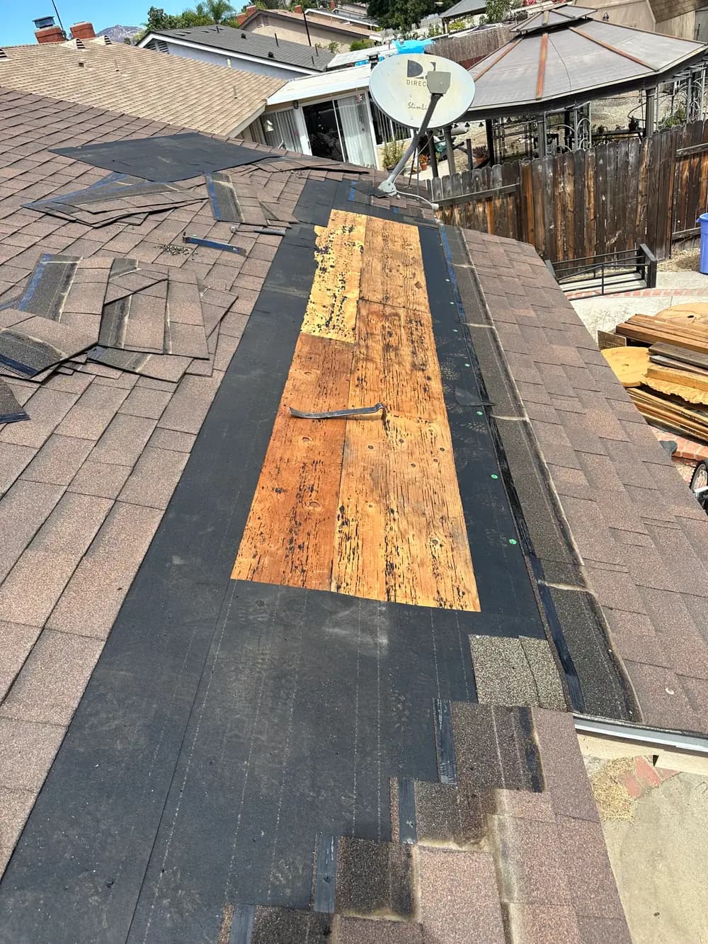 Exposed wood decking in a shingle roof repair area