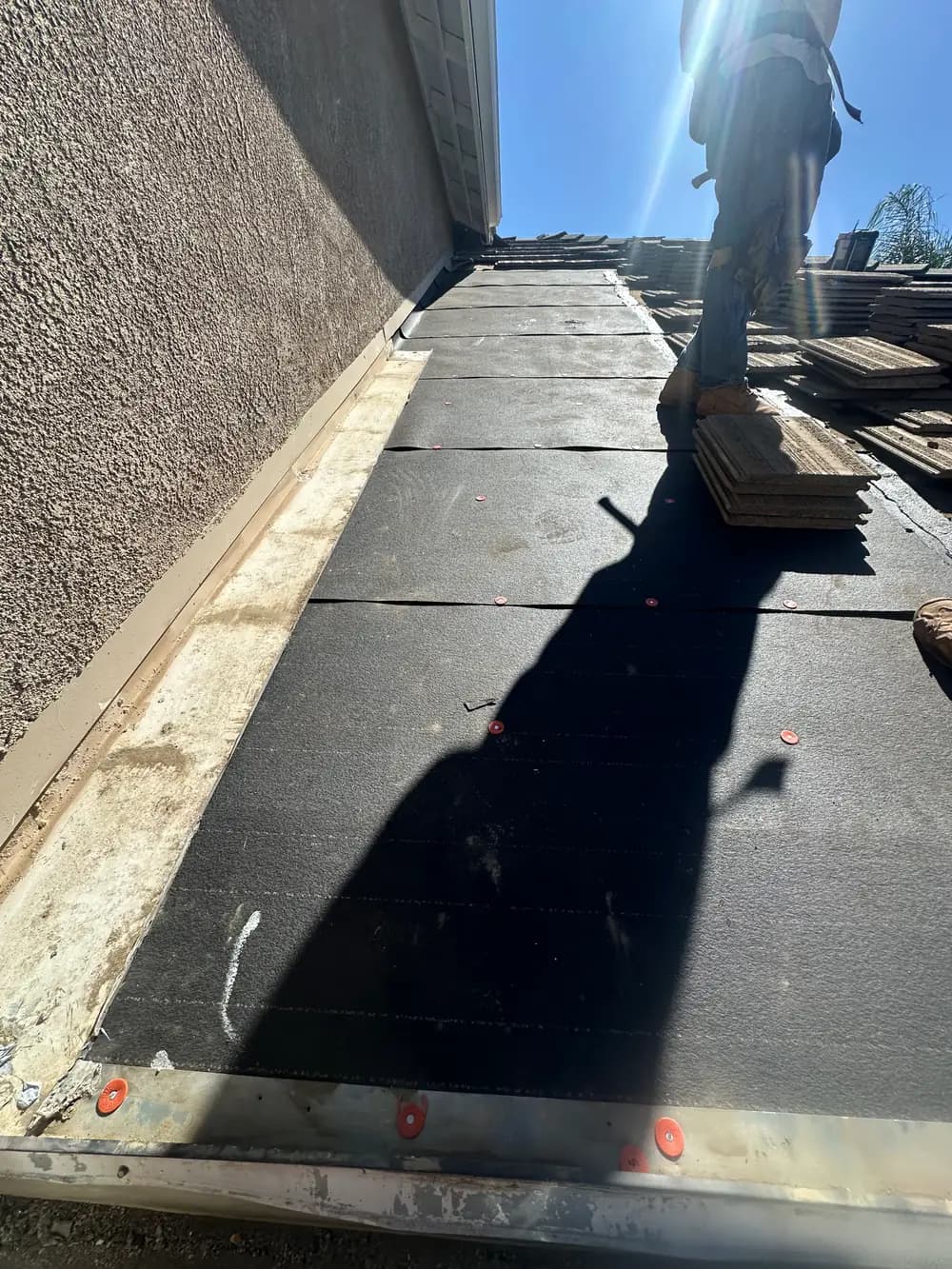 Underlayment visible with roof tiles stacked for reinstallation